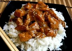 a black plate topped with rice and meat