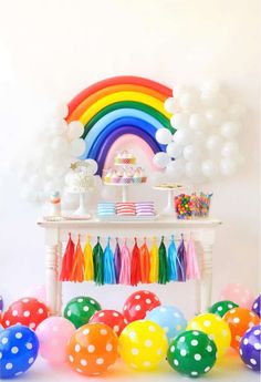 a table topped with balloons and rainbow decorations