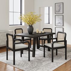 a dining room table with chairs and a vase filled with flowers on top of it