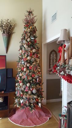 a decorated christmas tree in the corner of a living room with red and silver ornaments