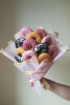 a person holding a bouquet of doughnuts with sprinkles