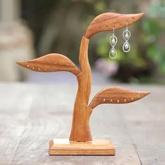 a wooden sculpture with earrings hanging from it's sides on top of a table