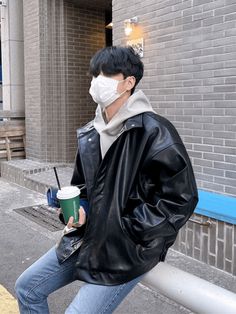 a man wearing a face mask and holding a cup while standing next to a building