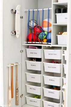 a white closet filled with lots of bins and baskets next to a baseball bat