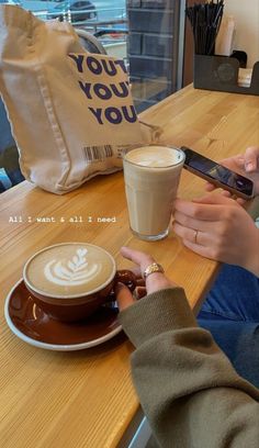 a woman sitting at a table with a cup of coffee and cell phone in her hand