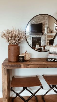 a wooden table topped with a mirror and two stools next to a fire place