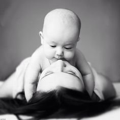 a black and white photo of a baby laying on its mother's back with her eyes closed