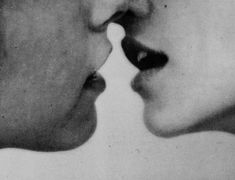 an old black and white photo of two people with their noses close to each other