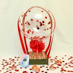 a clear glass ball with red bows and confetti on it sitting on a table