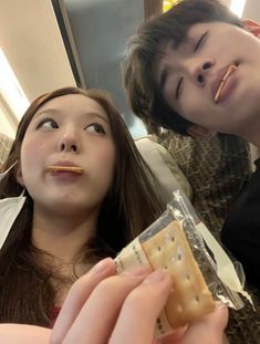 two young people are eating crackers together