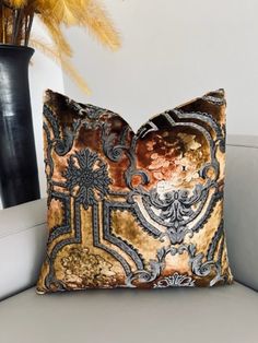 a decorative pillow sitting on top of a couch next to a vase with yellow flowers