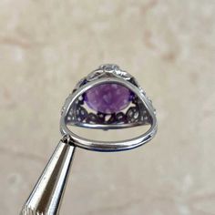 A bold gemstone ring featuring a 6.00 carat cushion-cut amethyst center stone that is set in prongs. Surrounding the amethyst are single-cut diamonds that are micro-pave set in a platinum bow motif. The total weight of the diamonds is approximately 0.62 carats. This ring is handcrafted in platinum.
The measurements of the center stone are approximately 11.84mm x 11.13mm x 8.36mm.
The current size of this ring is 7 and can be resized at no extra cost.
Ready to Make It Yours? Contact us to reserve White Gold Amethyst Ring With Gemstone Accents, Fine Jewelry Cushion Cut Amethyst Ring, Fine Jewelry Purple Cushion Cut Amethyst Ring, Cushion Cut Amethyst Ring For Formal Occasions, Formal Purple Amethyst Ring With Bezel Setting, Amethyst Ring With Gemstone Accents, Fine Jewelry Amethyst Cushion Cut Ring, Cushion Cut Purple Amethyst Ring, Formal Amethyst Ring With Round Stone