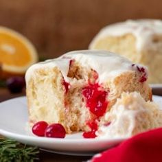 a piece of cake with white frosting and cranberry topping on a plate