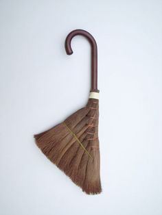 an umbrella shaped like a broom on a white background with the handle extended up to show it's brown color