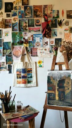 an easel is sitting in front of a wall covered with pictures and other items