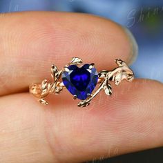 a close up of a person's hand holding a ring with a blue stone