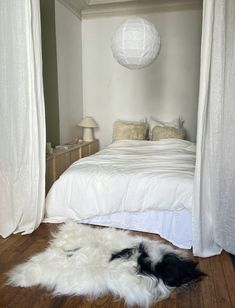 a white bed sitting in a bedroom next to a wooden floor