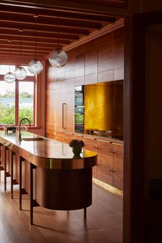 a kitchen with wooden cabinets and an island in front of a large window that looks out onto the water