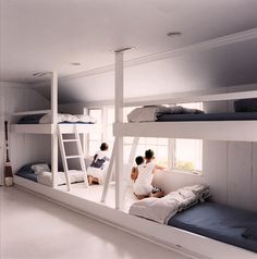 three people sitting on top of bunk beds in a room with white walls and floors