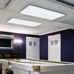 an empty room with blue walls and white trim on the ceiling is lit by recessed lights