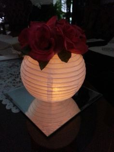 a white paper lantern with red roses in it