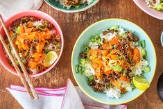 three bowls filled with rice, meat and veggies on top of a wooden table