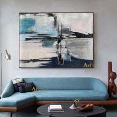 a living room filled with furniture and a painting hanging on the wall over a coffee table