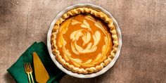 an overhead view of a pie on a table with utensils and napkins