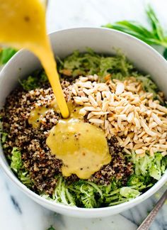 a white bowl filled with broccoli and sunflower seeds being drizzled over it