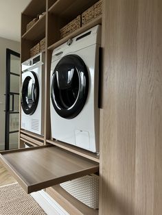 a washer and dryer in a room with wooden shelves on the wall next to each other