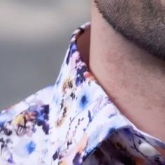 a close up of a man wearing a flowered shirt with his neck tie undone