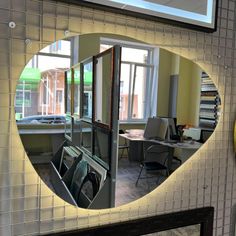 a mirror reflecting the inside of a room with chairs and desks in front of it