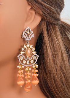 This beautiful necklace set in Peach boasts a premium quality dual-tone Tyaani with intricate Kundan detailing. It's the ideal accessory to add a touch of glamour to any special occasion, such as a runway show. Don't let this exquisite piece slip away! Necklace Length: 15" Neckline has an adjustable doori. Earring Lenght: 3.5" Push-Back closure Weight : 23 gms each. Dual-tone finish on high-quality brass as a base metal. Availability: In-Stock. *Color may vary slightly due to light condition & p Elegant Pink Chandbali Bridal Necklace, Orange Jewelry For Wedding And Diwali, Elegant Apricot Jewelry For Wedding, Elegant Peach Jewelry For Festive Occasions, Elegant Peach Jewelry For Formal Occasions, Orange Festive Jewelry For Celebration, Festive Orange Jewelry For Celebration, Elegant Formal Peach Jewelry, Elegant Peach Formal Jewelry