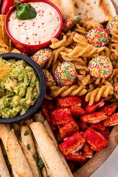 an assortment of snacks and dips on a platter with confetti, guacamole, tortillas