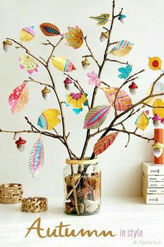 a vase filled with lots of different colored leaves on top of a white table next to a wall