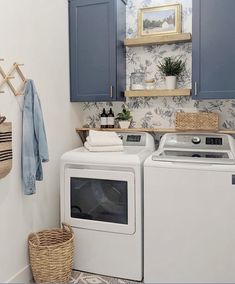 a washer and dryer in a small laundry room with blue cupboards on the wall