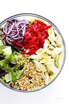 a bowl filled with lettuce, red peppers, and other ingredients to make a salad