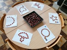 a wooden table topped with cards and a tray filled with beads on top of it