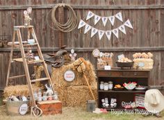 an outdoor party with hay bales and decorations on the side of a wooden fence