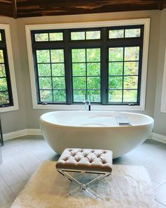 a large white bath tub sitting in a bathroom next to a window with lots of windows