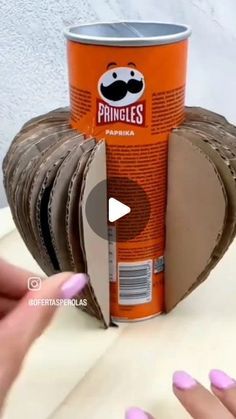 a can of pringles sitting on top of a table next to a woman's hand