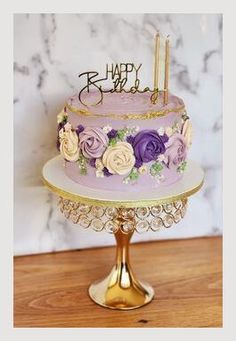 a purple and gold birthday cake sitting on top of a table