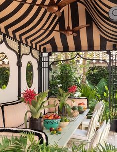 an outdoor dining area with black and white striped awnings, potted plants and chairs