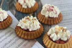 four small desserts sitting on top of a piece of paper next to music sheets