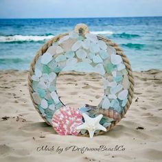 "Seaglass Wreath decorated with shells and a starfish. Finished with hemp rope and Felt backing. This Wreath is 6.5\" in diameter and can be Wall hung. This decorative piece is made using genuine Frosty White, Seafoam green and Ice aqua seaglass.  This Wreath is for indoor use only. A beautiful decorative Beach themed Wreath. This item weighs approx 300g not including packaging. Each piece will differ slightly due to seaglass and shells. However the design will be the same. Handcrafted by Driftw Seaglass Wreath, Beach Glass Wreath, Beach Themed Wall Art, Seashell Creations, Sea Glass Diy, Sea Glass Mosaic, Seashell Wreath, Coastal Christmas Decor, Decorative Wall Hanging