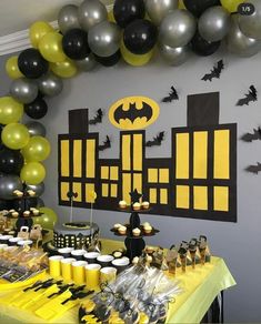 a batman themed birthday party with black, yellow and silver balloons hanging from the ceiling