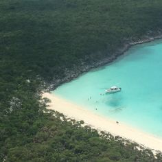 a boat that is sitting in the water near some sand and green trees on an island