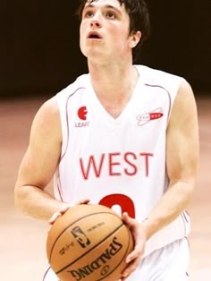 a young man holding a basketball on top of a court