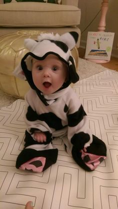 a baby in a zebra costume sitting on the floor