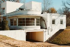 an old white building with stairs leading up to the top floor and second story window